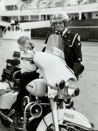 Princely perch: Sergeant Campbell Wood props Prince Harry on a police motorcycle Saturday near royal yacht