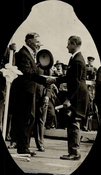 The Prince of Wales and Vice-President Dawes of the United States shaking over the ribbon marking tional boundary at the offi of the Peace bridge. [Incomplete]