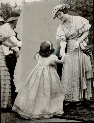 Curtsy for the Queen-A little girl curtsies to the Queen as she presents a purse at a garden party for charitable purposes at St. James palace