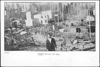 Black and white pictured of the beginnings of frame houses being erected in a mining camp.