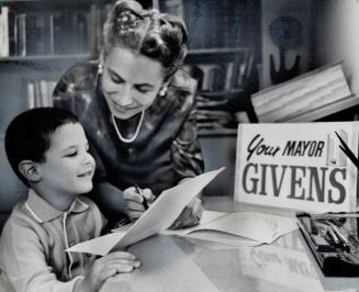 Mayor Givens' campaign literature is looked after by his wife, Min, who uses her commercial artist training to see that brochure designs are good. Son(...)