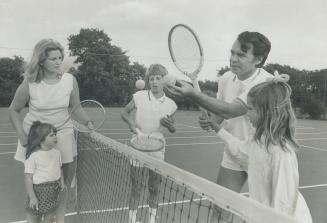 Image shows the Gordon family learning how to play tennis.