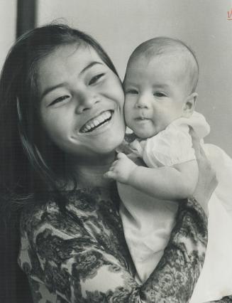 Mrs. Tom Gould, here cuddling her son, Thomas Nguyen, 2 1/2 months, had to make difficult transition from nightclub singer in Saigon to houswife in Ot(...)