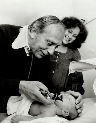 Dr. Joe Greenberg checks over Jacqueline, three-week old daughter of Cheryl Levitt, centre