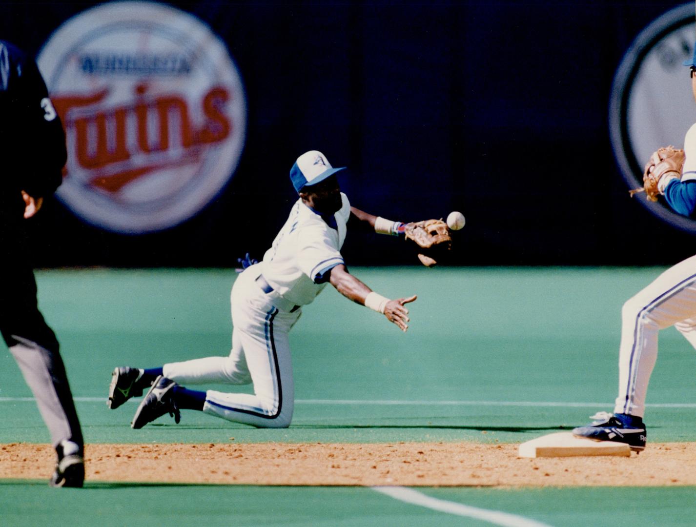 Call it two: Alfredo Griffin snares a hot smash up the middle and shuffles the ball to Roberto Alomar, who avoids Ranger Dan Peltier to turn a double play yesterday