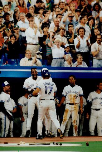 Fan-tastic: Fans, as well as Joe Carter and other Blue Jay players, were on their feet to welcome Kelly Gruber back to the dugout after his two-run blast