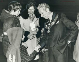Gregory Donn shakes hands with Gus Harris as brother Fraser and mother Anne look on