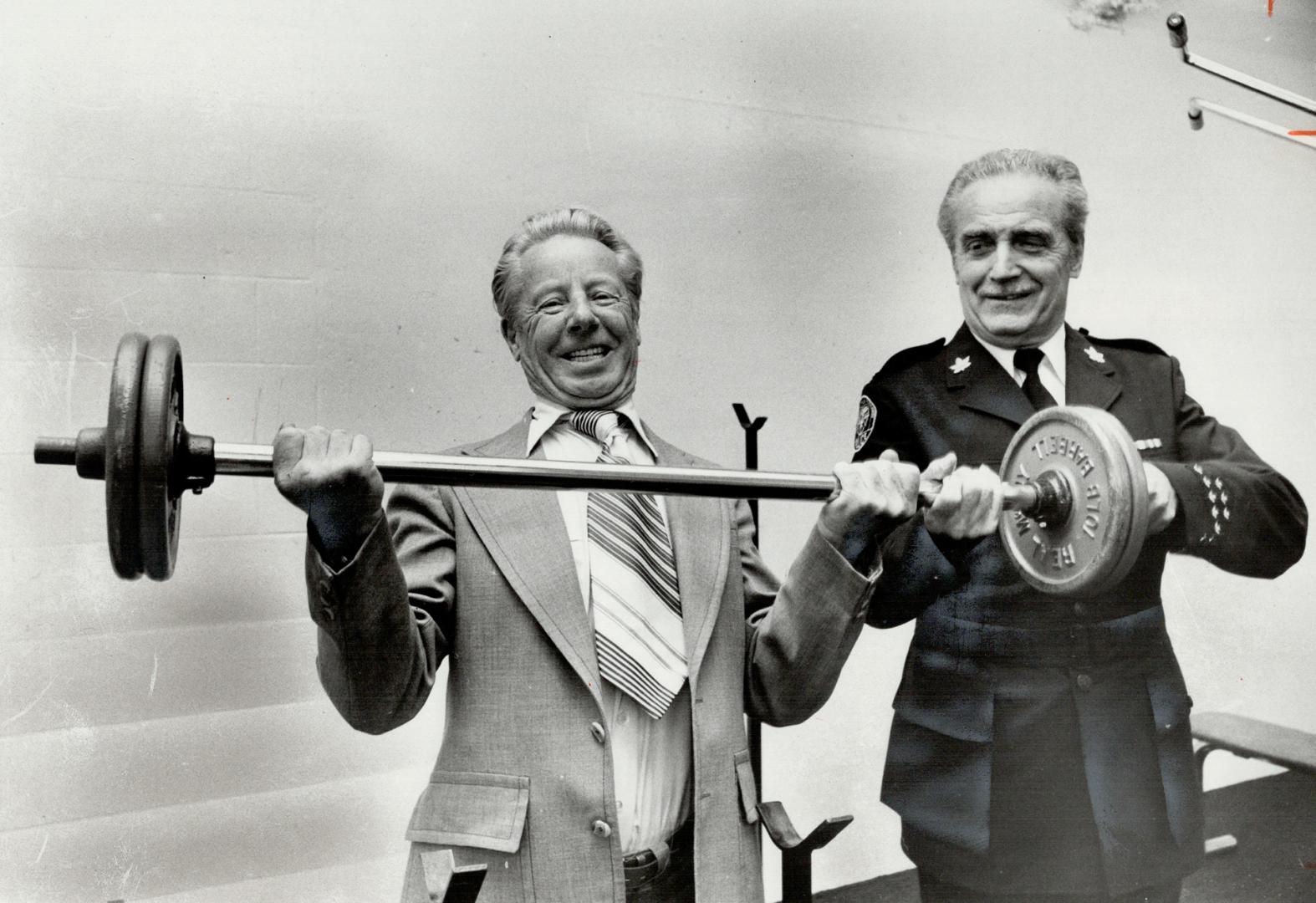 Mayor Gus Harris lifts 40-pound weights as Inspector Cyril Cole helps