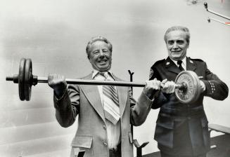 Mayor Gus Harris lifts 40-pound weights as Inspector Cyril Cole helps