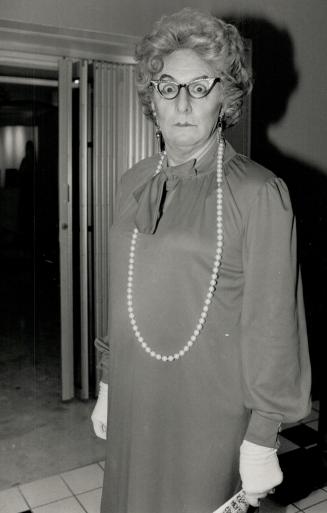 Actor Don Harron, dressed for his Valerie Rosedale character, looks chic in a Claire Haddad red polyester dress with opera length pearls