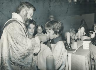 Rev. Daniel Heap administers communion to young worshipper during service at Holy Trinity Church. Readers below criticize attack on St. John's (Norway(...)