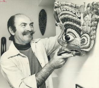 Jules Heller, dean of the fine arts department at York University, finds just the spot in his apartment to hang this dramatic mask from Sri Lanka (Cey(...)