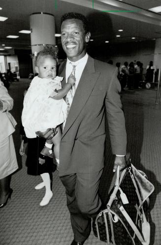Oakland A's star Rickey Henderson carries daughter Alexis, 13 months, through Pearson airport last night