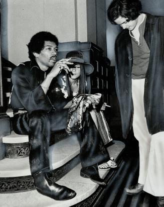 Awaiting his day in court. Pop singer Jimi Hendrix (left), charged with illegal possession of narcotics, and a friend wait in old city hall for court (...)