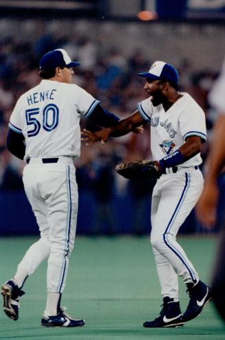 Slap happy: Save-master Tom Henke and bashing outfielder Joe Carter celebrated last night's nailbiting win over the Tigers
