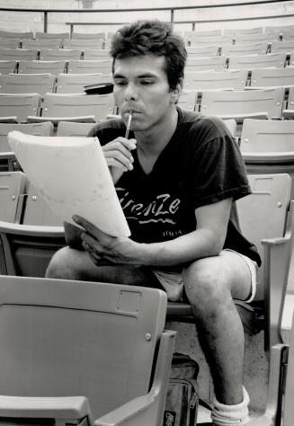 A young man ponders a script in an empty theatre.