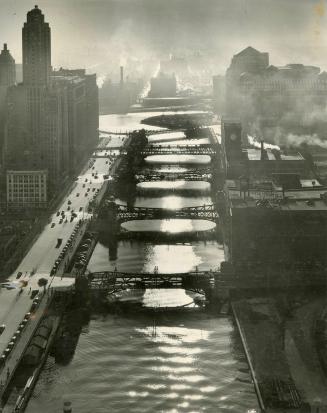 This striking picture of rows of bridges across the Chicago river in the city's hear, shows a photographer needs no mountains to reach a camera height. The skyscraper, left is the world's largest office edifice.
