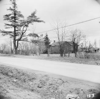 Image shows a limited view of a house and many trees along the road.