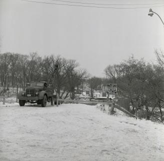 Old Dundas St., looking east across Humber River, showing truck drawing up sections of bridge after it was toppled into the river