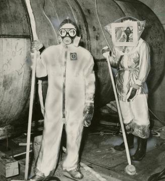 Protective clothing à Plastic suits and respirators are used to protect workers at Canadaïs Chalk River, Ontario, atomic plant from deadly radioactivity