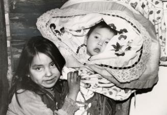 Natalie Kam takes care of her 10-month-old brother, Nathaniel, who is carried in a tikinagan