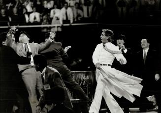 Benny Hinn: At left, and above, during Maple Leaf Gardens performance where he waved his coat about, proclaiming people cured of their ailments