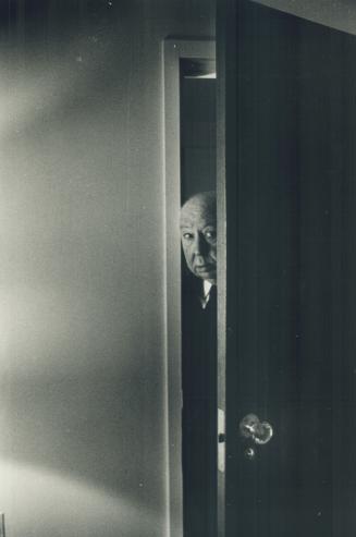 Director Alfred Hitchcock peers from his Royal York Hotel suite