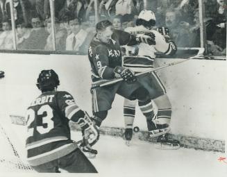 Gordie Howe of Houston Aeros holds Toronto Toros' Rick Cunningham against boards in WHA action at Varsity Arena last night. Howe was off form in a 5-2(...)