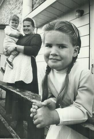 She is shown leaning on farmhouse veranda as mother: Suzy holds baby brother Gerald in background
