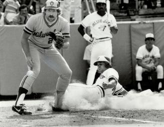The tying run: Pinch-runner Garth Iorg slides across home plate to tie the score at 3-3 in the eighth inning of yesterday's game as Brewer pitcher Pete Ladd awaits the throw