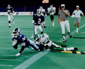 Hang on tight: Saskatchewan's Lucius Floyd brings down Rocket Ismail after another lengthy return during last night's 62-10 blowout at the SkyDome