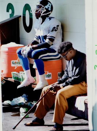 Down and out in Hamilton: A dejected Raghib (Rocket) Ismail found a cooler place to sit at Ivor Wynne: while an injured Mike (Pinball) Clemons bows his head and wishes he could have played yesterday