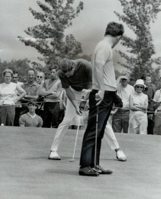 Tony Jacklin (right), British Open golf champ, glances over his shoulder at the putting style of Doug Sanders in yesterday's opening round of the Cana(...)