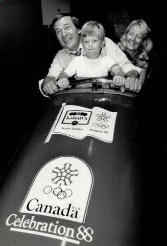 That Calgary spirit: Federal Sport minister Otto Jelinek, his wife Leata and son Misha, 4 try out a bobsleigh simulator at Olympic Celebration '88 Caravan, at the CNE Coliseum