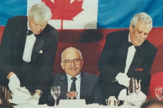 King Hussein of Jordan is flanked by two waiters during a banquet at the Royal York Hotel, where he addressed a joint meeting yesterday of the Canadia(...)