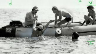 Coach, Dave Shakeshaft, (in boat, at right) and other unidentified people help him into a rubber boat