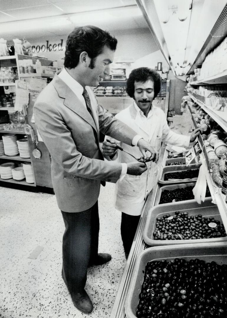 Liberal candidate Robert Kaplan, campaigning in York Centre, tastes an olive offered by grocery store manager Jim Ferlisi. Kaplan calls the riding completely Liberal. His opponents says no