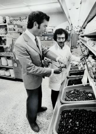 Liberal candidate Robert Kaplan, campaigning in York Centre, tastes an olive offered by grocery store manager Jim Ferlisi. Kaplan calls the riding completely Liberal. His opponents says no
