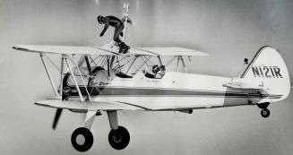Up on his feet on top of the wing of his plane during yesterday's performance of aerial stunts at Niagara Falls, John Kazian moves forward to take his(...)