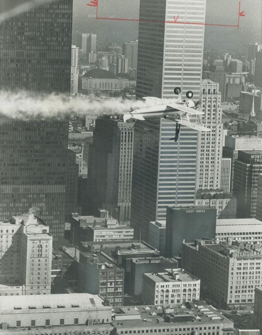 Just hanging around downtown. Wing walker John Kazian hangs from top wing of airplane while pilot Joe Hughes flies upside down past Toronto-Dominion C(...)