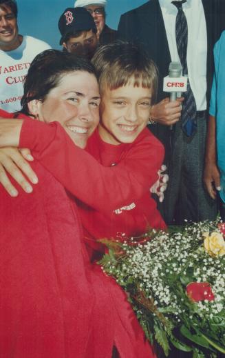 Swimmer Vicki Keith emerges from Lake Ontario yesterday to a hug from 13-year-old Jeremy Ein, the Variety Club poster child. Keith was happy she compl(...)