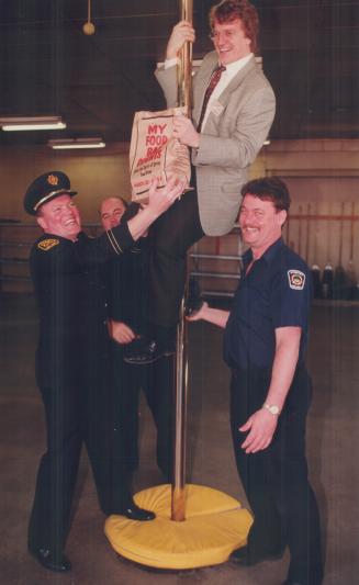 Food slide: Food bank's Gerard Kennedy clowns with Firefighters Bob Webb, left, Bob Smith and Brian Boyd at Etobicoke firehall 3