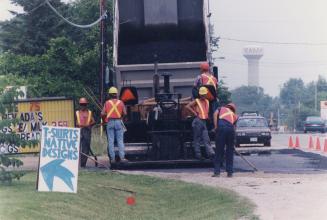 Construction workers laying down asphalt