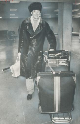 Soviet poet Yevgeny Yevtushenko, who gained an international reputation in early 1960s with emotional poetry that offened Moscow, pushes his luggage i(...)