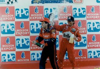 Party time: Third-place finisher Emerson Fittipaldi, right, douses Indy winner Michael Andretti with the traditional bubbly on the podium yesterday