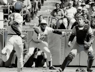 He scores! Jays' Lloyd Moseby (centre) yells encouragement as Danny Ainge heads for home plate to score a run yesterday in the sixth inning of the Jay(...)