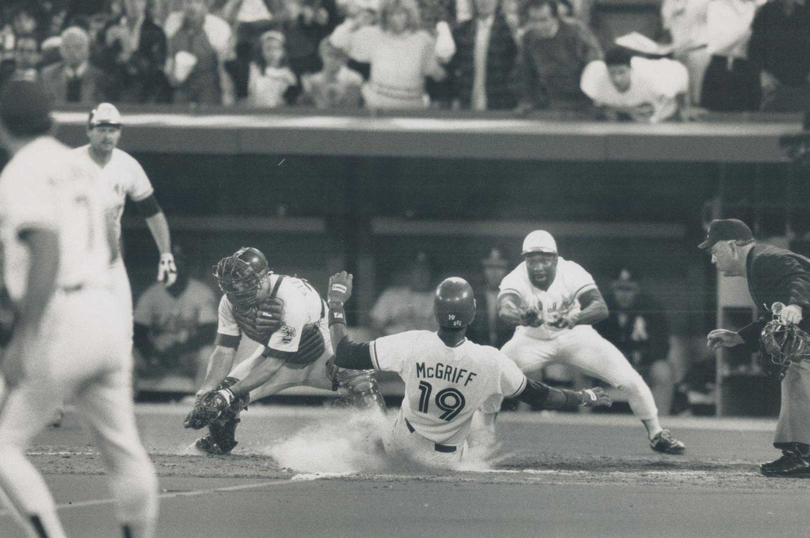 Hit it! Fred McGriff takes Mookie Wilson's advice and hits the deck as he scores Jays' third run in a four-raun fourth inning. A's catcher Terry Steinbach wits for the late throw