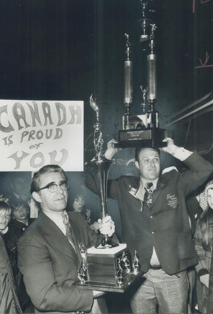 Triumphant return: Sponsor Vern Dynes (left) and manager Stan Thornington carry world softball trophies won by Richmond Hill Dynes, through crowd
