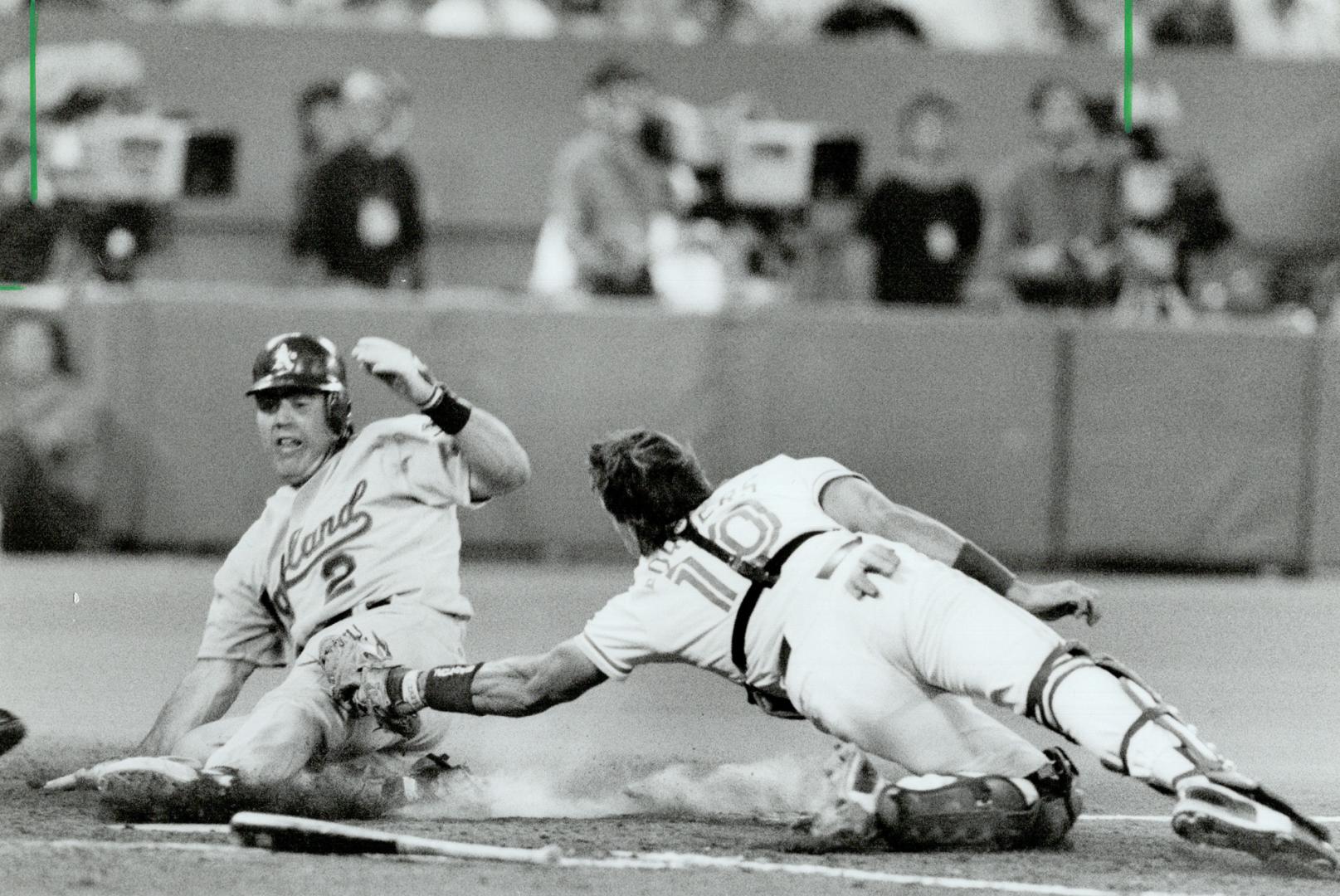 Winning slide: Oakland's Scott Hemond slips in safely under the tag of catcher Pat Borders to score the go-ahead run in the ninth inning last night