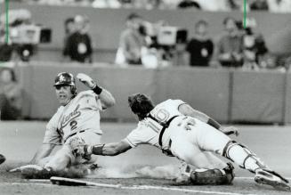 Winning slide: Oakland's Scott Hemond slips in safely under the tag of catcher Pat Borders to score the go-ahead run in the ninth inning last night